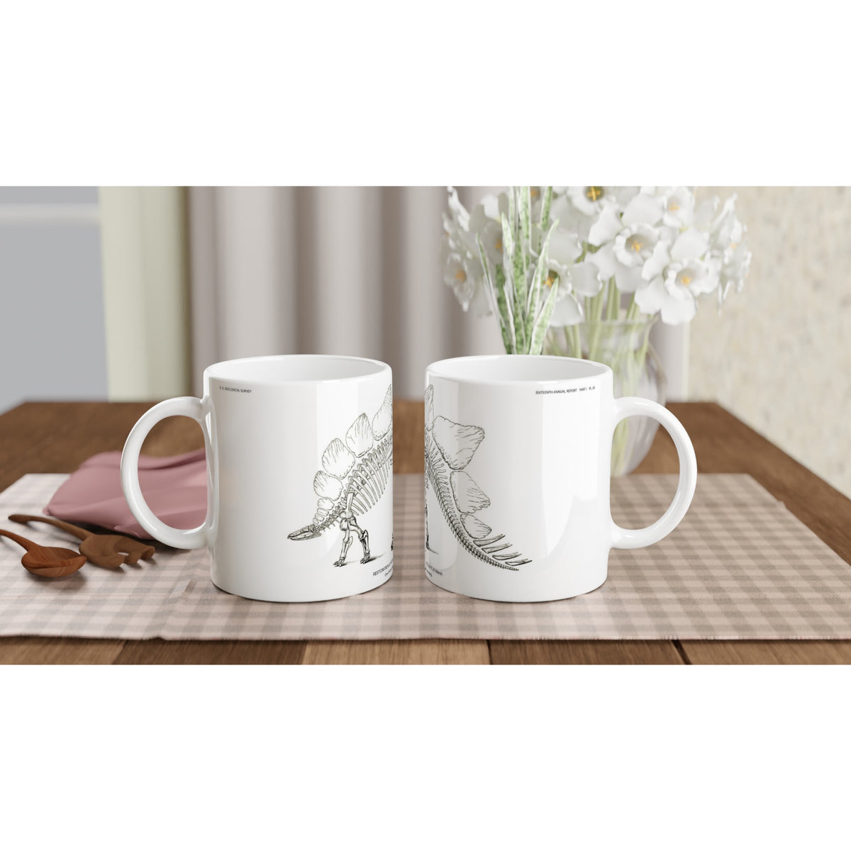 Mug en céramique illustré d'une gravure scientifique de squelette de Stégosaure. Mug en céramique blanche illustré d'une gravure scientifique représentant le squelette d'un Stégosaure avec la mention textuelle U.S. Geological Survey.