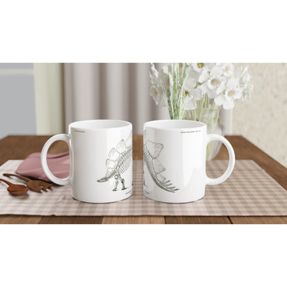 Mug en céramique illustré d'une gravure scientifique de squelette de Stégosaure. Mug en céramique blanche illustré d'une gravure scientifique représentant le squelette d'un Stégosaure avec la mention textuelle U.S. Geological Survey.