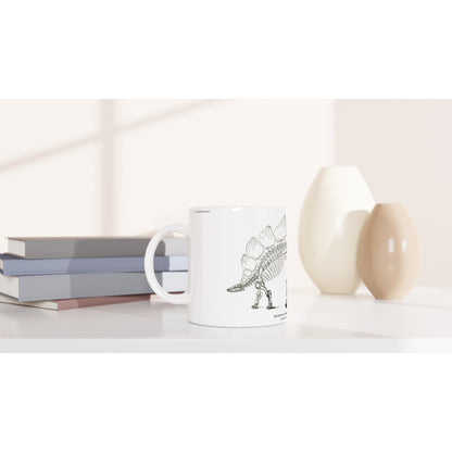 Mug en céramique illustré d'une gravure scientifique de squelette de Stégosaure. Mug en céramique blanche illustré d'une gravure scientifique représentant le squelette d'un Stégosaure avec la mention textuelle U.S. Geological Survey.
