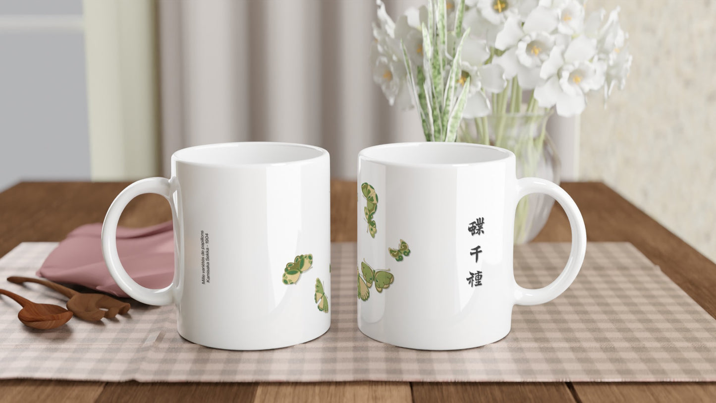 Planche de papillons bleus et verts en arc, Kamisaka Sekka. Mug blanc avec une illustration de papillons aux ailes bleues et vertes, bordées de motifs dorés, disposés en un arc de cercle, accompagnés d'un texte en calligraphie noire. Image d'illustration 2